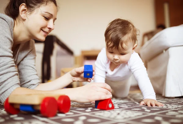 Baby flicka som leker med sin mor på en matta — Stockfoto