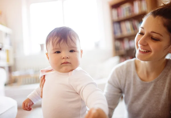 Meisje van de baby spelen met haar moeder op een tapijt — Stockfoto