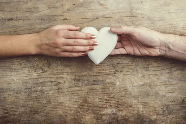 Manos conectadas a través de un corazón blanco . — Foto de Stock