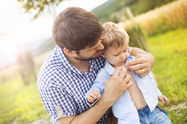 Little boy getting dressed by his father.