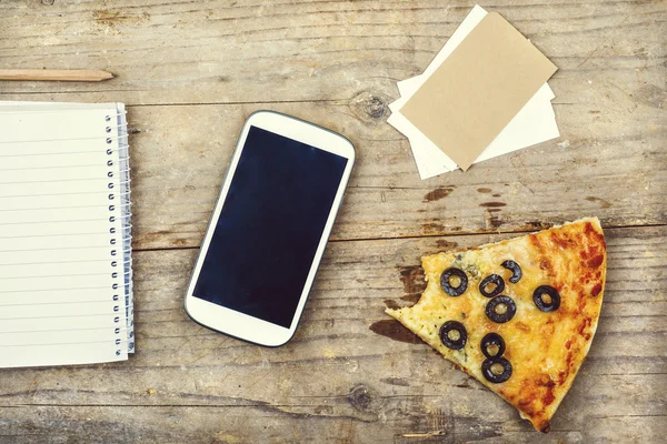 Smart telefon, kontorsmaterial och pizza — Stockfoto