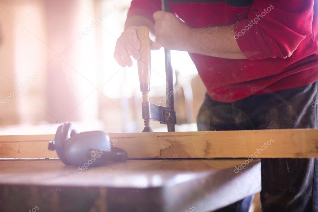 Carpenter screwing a glue clamp