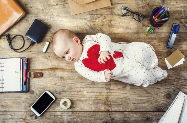 Desk with office supplies and little baby — Stock Photo, Image