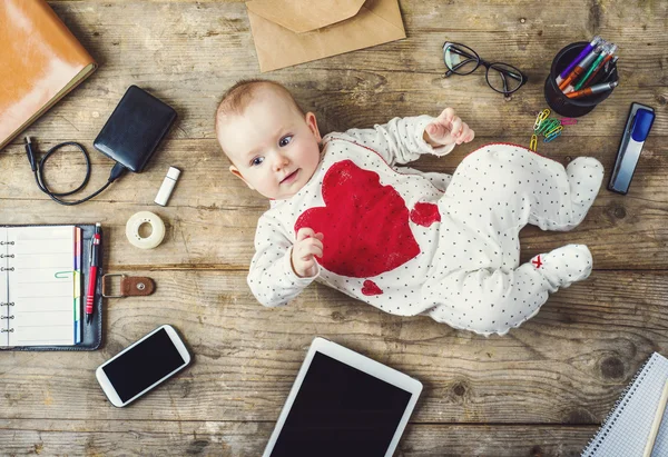 Escritorio con suministros de oficina y bebé pequeño — Foto de Stock