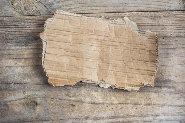 Piece of carton on wooden floor — Stock Photo, Image