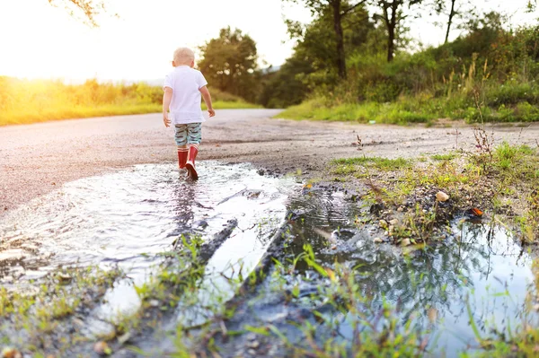 Little boy playing in a puddle — Stock Photo, Image