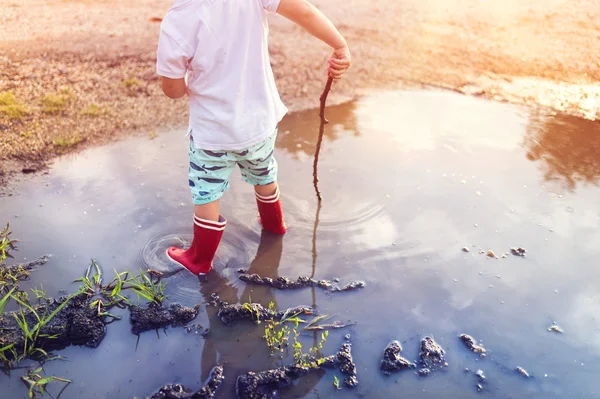 Kleiner Junge spielt in einer Pfütze — Stockfoto