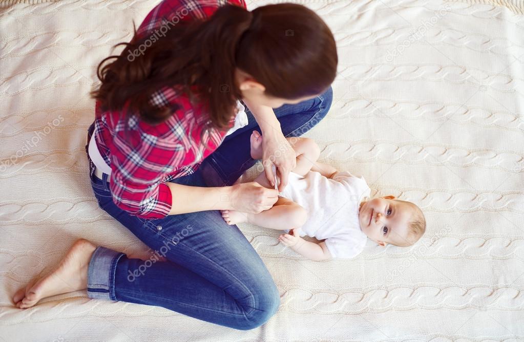 Baby girl getting dressed by her mother