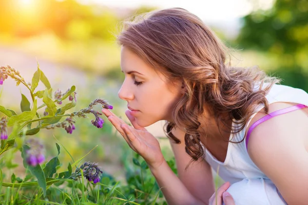 Frau riecht Blumen auf einer Wiese. — Stockfoto