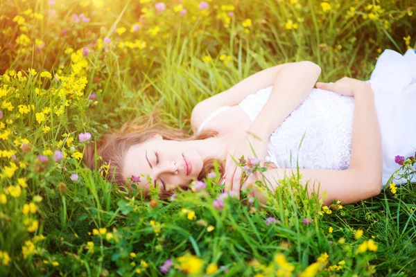 Vrouw liggend op een weiland vol met bloemen. — Stockfoto