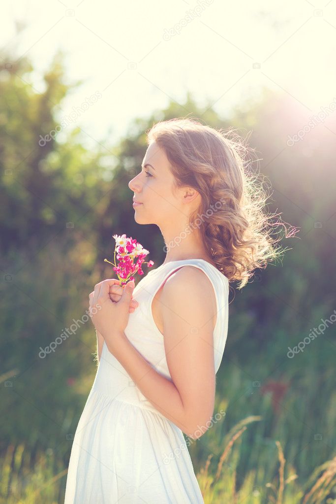 Woman holding flowers  on a meadow.
