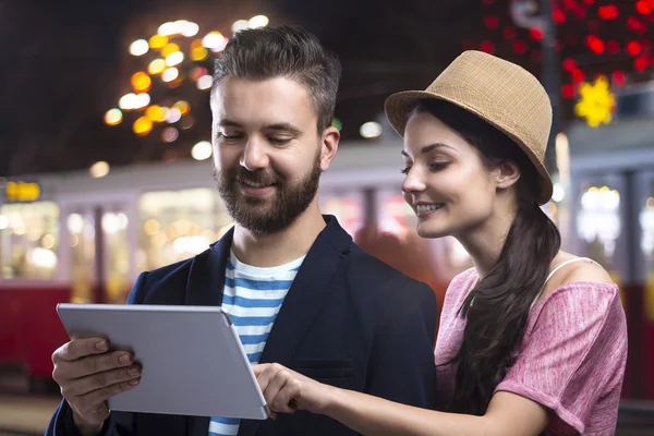 Coppia con un tablet godendo la vita notturna — Foto Stock