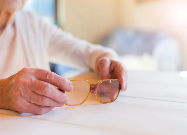 Starší žena hospodářství brýle — Stock fotografie