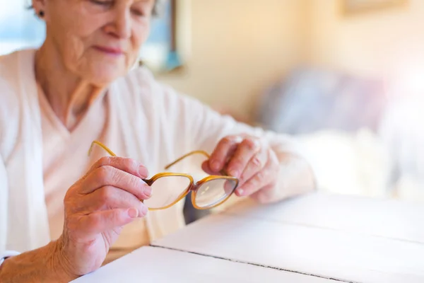 Mujer mayor sosteniendo gafas —  Fotos de Stock