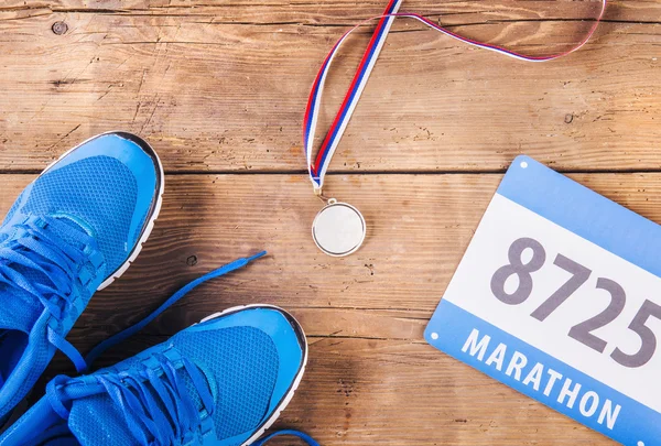 Running shoes, medal and race number — Stock Photo, Image