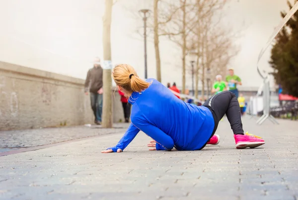 Бегущая женщина падает на землю — стоковое фото
