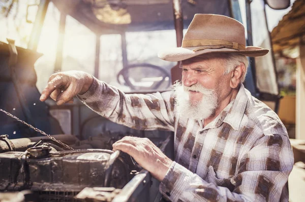 Fermier âgé réparant un tracteur — Photo