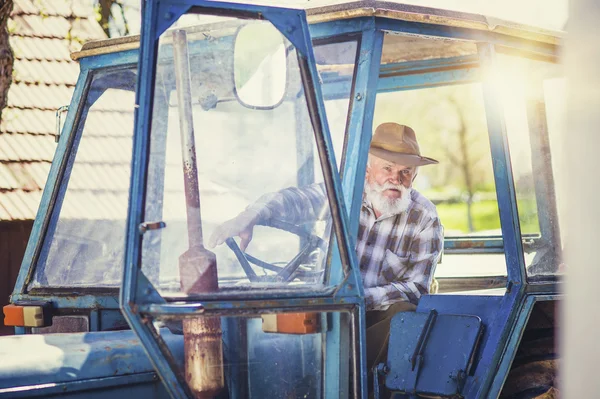 Senior bonden kör en traktor — Stockfoto