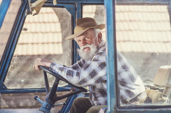 Senior landbouwer rijden een trekker — Stockfoto