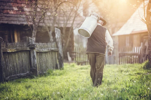 Agricoltore che trasporta latte bollitore — Foto Stock