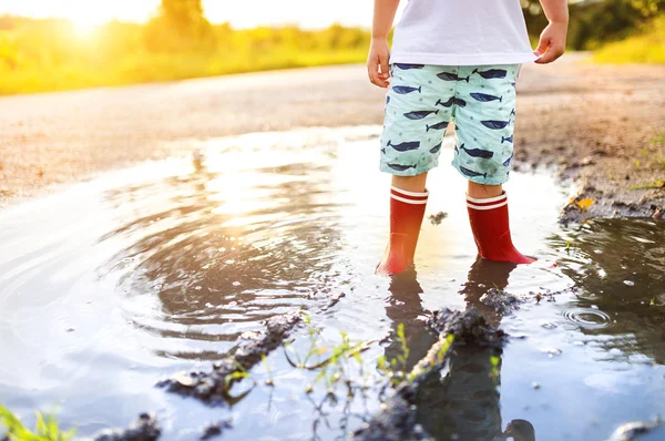 Kleiner Junge spielt in einer Pfütze — Stockfoto