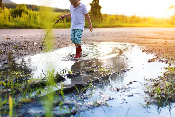 在一个水坑里玩耍的小男孩 — 图库照片