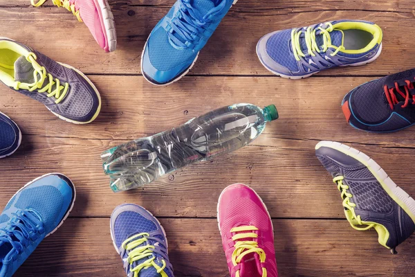 Verschillende loopschoenen met fles water — Stockfoto