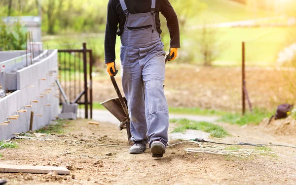 Maurer geht mit leerer Schubkarre — Stockfoto