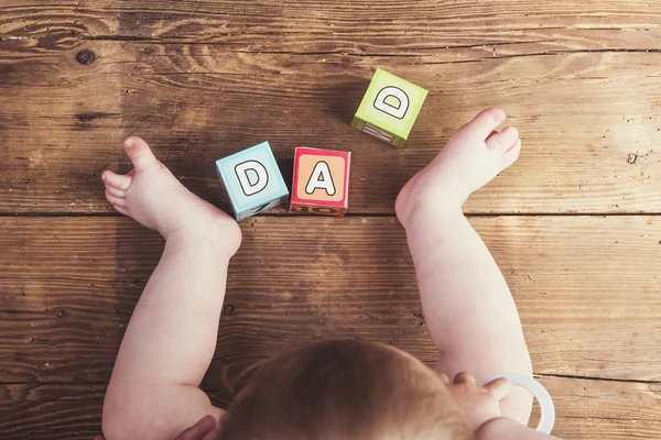 Lilla bebis med kuber och pappa tecken — Stockfoto