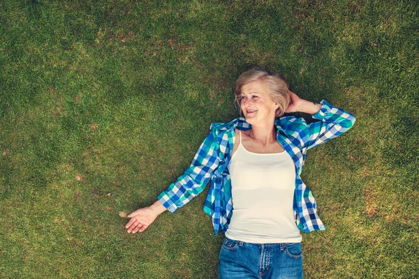 草の上に横たわる年配の女性 — ストック写真
