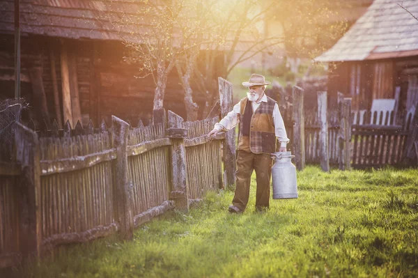 Su ısıtıcısı süt tam taşıyan kıdemli çiftçi — Stok fotoğraf