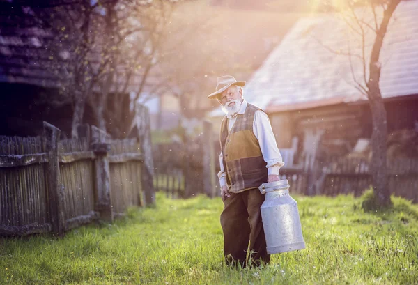 Fermier âgé portant une bouilloire pleine de lait — Photo