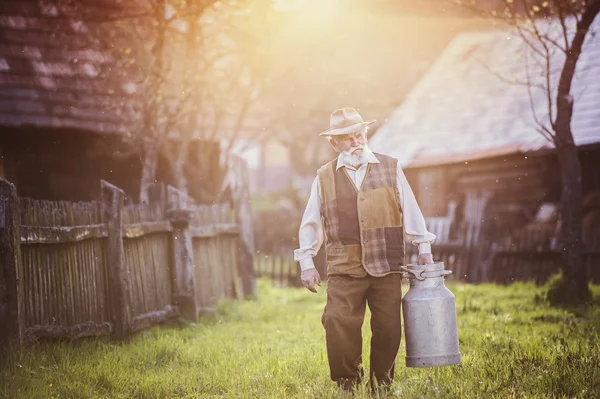 Senior landbouwer uitvoering waterkoker vol van melk — Stockfoto