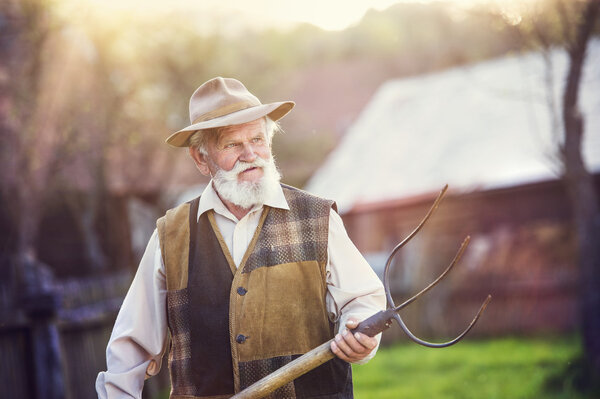 Old farmer with pitchfork taking a break