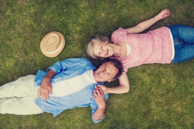 Senior couple lying on a grass and hugging