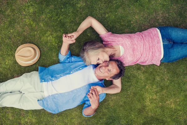 Casal sênior deitado em uma grama e abraçando — Fotografia de Stock