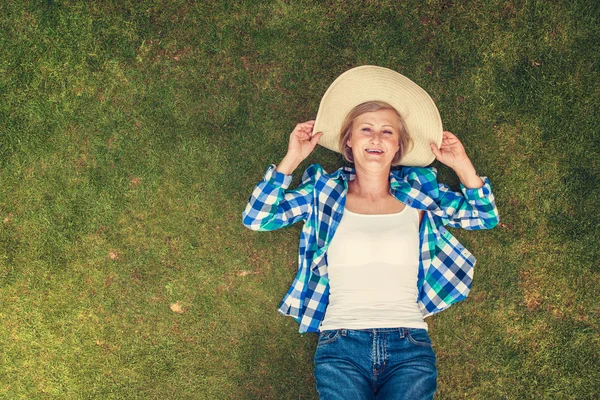 Mulher sênior deitada em uma grama — Fotografia de Stock