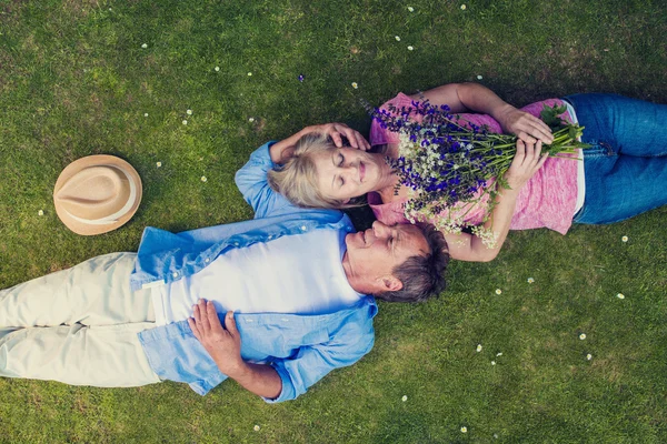 Beautiful senior couple lying on a grass a — Stockfoto