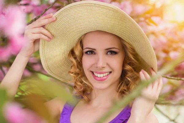 Femme en chapeau posant en fleurs roses — Photo