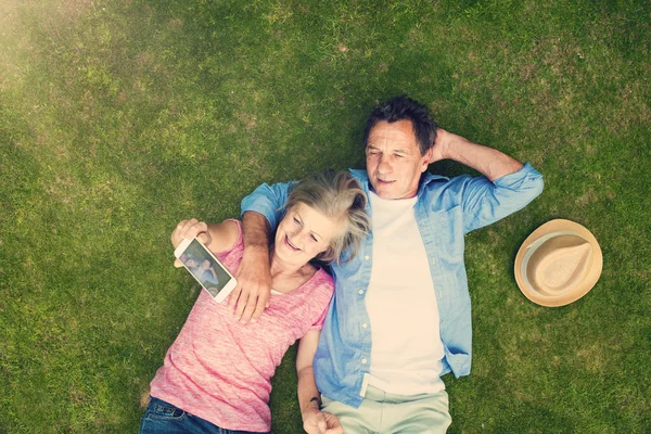 Beautiful seniors lying on a grass — Stock Photo, Image