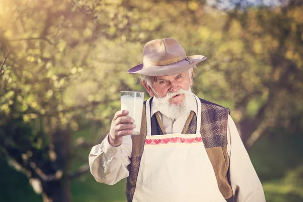 Agricoltore anziano con un bicchiere di latte — Foto Stock