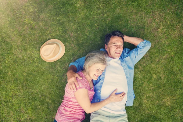 Senioren liggend op een gras in een park — Stockfoto