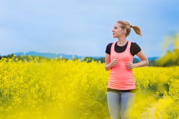 Woman running in spring canola field — Stock Photo, Image