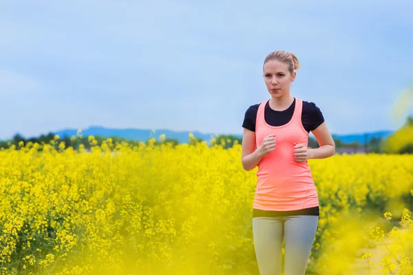 Woman running in spring canola field — 图库照片