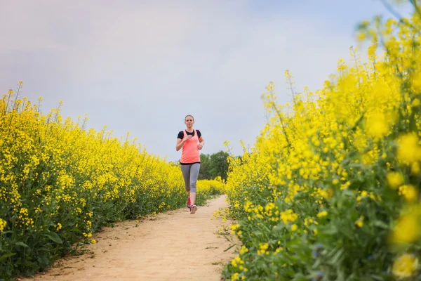 Woman running in spring canola field — Stok fotoğraf