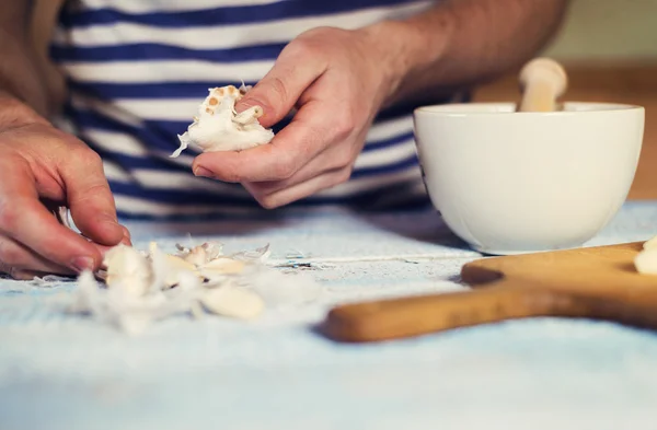 Man peeling garlic cloves for a dressing — Stock Photo, Image