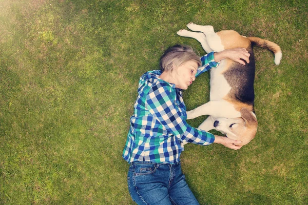 高级女人与她的狗躺在草地上 — 图库照片