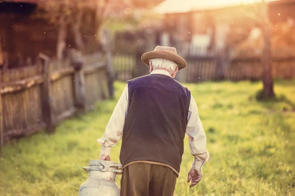 Agricoltore anziano che trasporta bollitore pieno di latte — Foto Stock