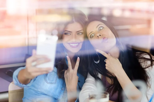 Två vackra kvinnor som tar selfie i café — Stockfoto