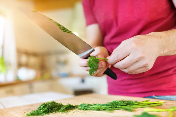 Hombre en la cocina cortando eneldo — Foto de Stock